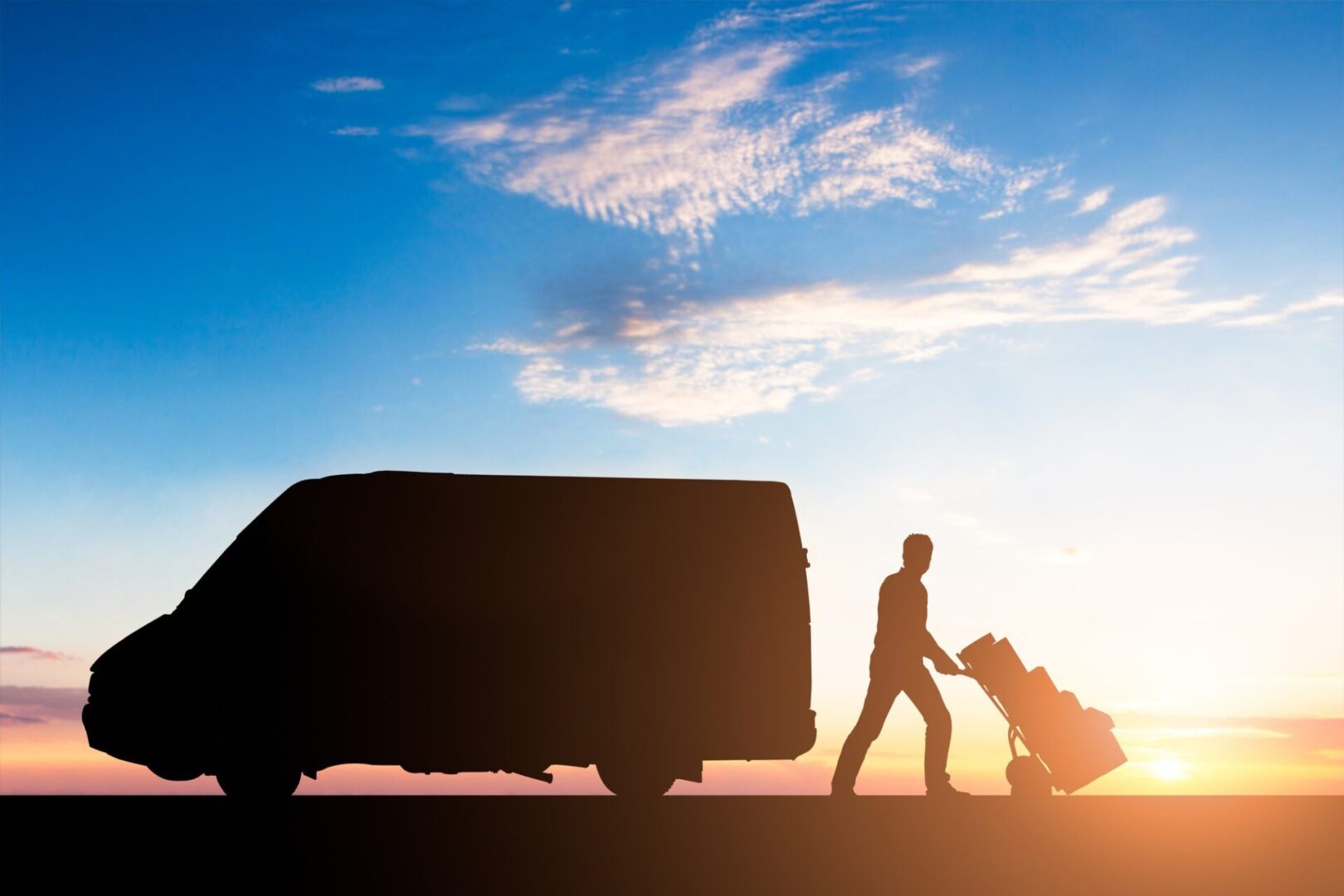 Silhouette Of Delivery Courier With Cardboard Boxes On Trolley Near The Van At Sunset